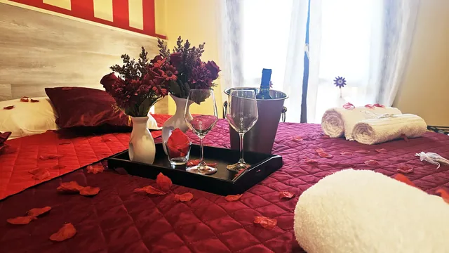 Allestimento Romantic Room con petali di rosa e vino